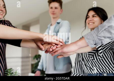 Friendly group of people doing handshake and cross hands. Friendship, agreement, cooperation concept with young teens crossing their hands