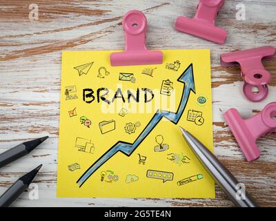 BRAND development and growth concept. Yellow sticky note on a wooden table. Stock Photo