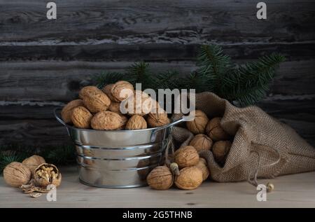 walnuts in a bowl and a sack on wooden table and a spruce branch Stock Photo