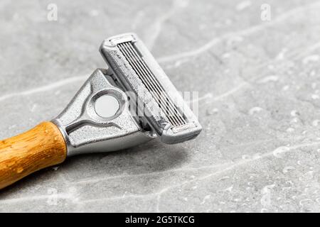 Wet shaving Razor with five blades head and wooden handle on a grey marble background. Macro shot Stock Photo