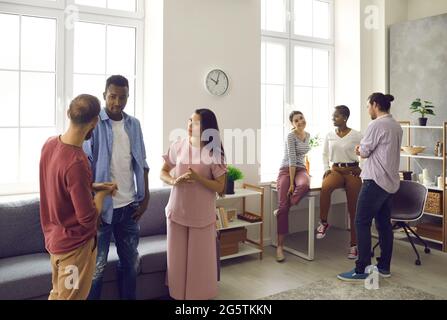 Friends stand in a room at home and communicate with each other. Stock Photo