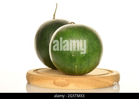Two dark green organic watermelons on a round wooden tray, close-up, on a white background. Stock Photo