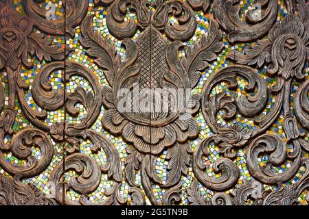 Lanna artwork, wood carving, high relief decorated with colorful glass. Northern Thai Arts Stock Photo