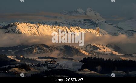 Aussicht auf das Emmental mit Berner Voralpen mit der beleuchteten Schrattenfluh und und Alpen (Wetterhörner im Hintergrund) von der 'Lueg' aus in der Stock Photo