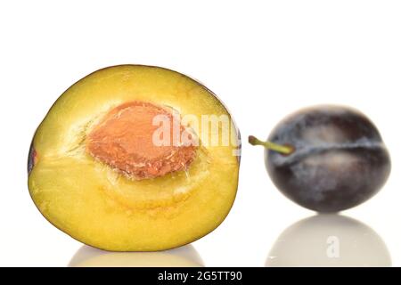 One half, in focus, ripe plum, close-up, isolated on a white background. In the background is one plum. Stock Photo