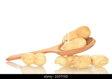 Ripe unpeeled peanuts with a wooden spoon, close-up, isolated on a white background. Stock Photo