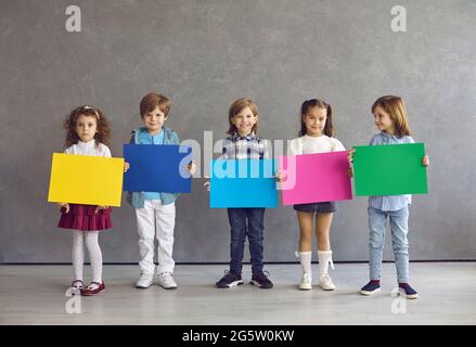 Diverse children group standing in row holding empty blank color poster Stock Photo