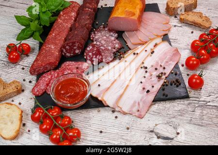 Slicing of different types of smoked sausage and meat on a wooden background. top view Stock Photo