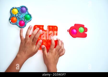 A child with a colorful pop it game. Anti-stress. A close-up shot of children's hands playing with the popular pop It fidget toy. Stock Photo
