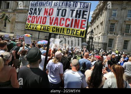 London, UK. 14th June, 2021. Protesters block Whitehall, and a large banner is seen reading ''Government is lying to you say no to the Covid Vaccine, Save the Children'' during the protest.Protesters gather outside Downing Street to protest against Boris Johnson's announcement of an extension of the lockdown regulations in the UK which they believe infringe their human rights they also protest against continued wearing of masks and being subjected to the vaccination program. Credit: Martin Pope/SOPA Images/ZUMA Wire/Alamy Live News Stock Photo