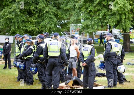 London, UK - 17 June 2021: A protestor is detained by police during the eviction of the lovedown anti-lockdown camp on Shepherds Bush Green. Stock Photo