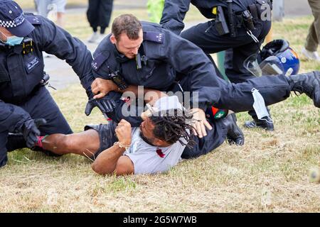 London, UK - 17 June 2021: A protestor is tackled to the ground by police following the eviction of the lovedown anti-lockdown camp on Shepherds Bush Green. Stock Photo