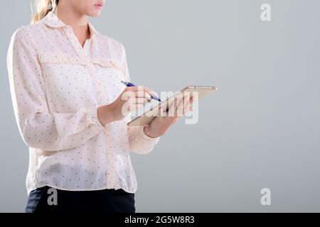 Caucasian businesswoman using graphic tablet, isolated on grey background Stock Photo