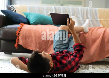 Asian boy using tablet with blank screen lying on floor at home Stock Photo