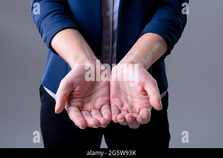 Midsection of caucasian businesswoman showing her hands, isolated on grey background Stock Photo