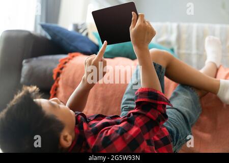 Asian boy using tablet with blank screen lying on floor at home Stock Photo