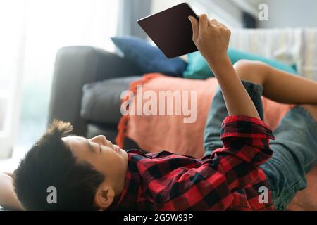 Asian boy using tablet with blank screen lying on floor at home Stock Photo