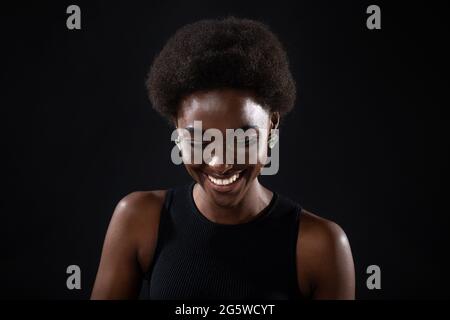 Young black positive african american woman laughing portrait on black background Stock Photo