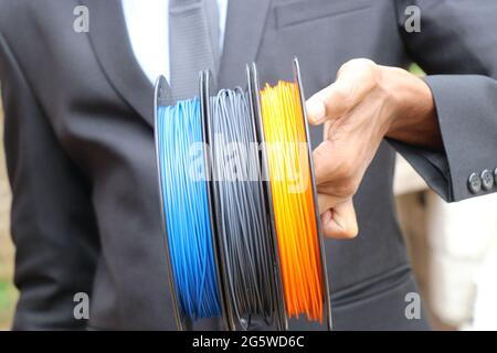Businessman showing 3D printer filament made from renewable resources. Different colors PLA filament for 3D printer made from bio plastic Stock Photo
