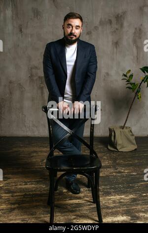 A young brutal bearded man in a suit stands in the studio. High quality photo Stock Photo