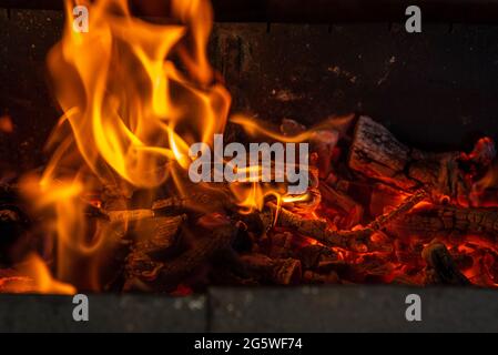 Glowing embers in hot red color. The hot embers of burning wood log fire. Firewood burning on grill. Abstract background. Stock Photo
