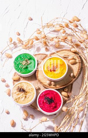 Various hummus dips, the flat lay of hummus in different colors with spinach, beetroot, turmeric and vegetables, vegan snack. White putty background, Stock Photo