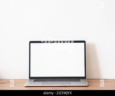 Home office wood desk with open laptop with white blank screen for text. Front view. Copy space Stock Photo