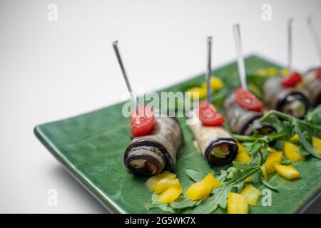close up of eggplant rolls with cream cheese on green plate on white background Stock Photo
