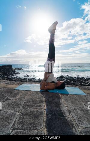 woman in sport clothes practicing yoga and meditating on beach in morning Stock Photo