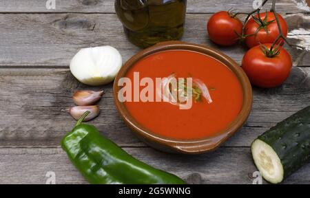 Gazpacho andaluz, made with tomatoes, onion, garlic, green bell pepper and olive oil, typical drink from the south of spain, from andalucia on a woode Stock Photo