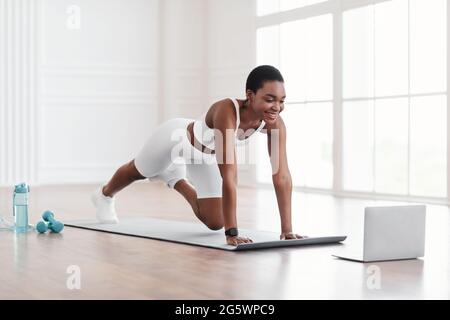 Young African Woman Doing Cross Body Mountain Climbers Exercise Stock Photo