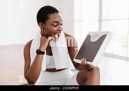 Portrait of African Woman Holding And Looking On Scales. Slimming Stock Photo