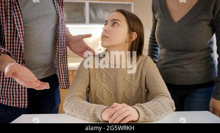 Upset teenage girl looking at parents shouting and abusing her. Family violence, conflicts and relationship problems Stock Photo