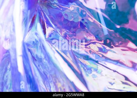 Defocused iridescent holographic background. Blurred colorful texture of wrinkled foil. Stock Photo