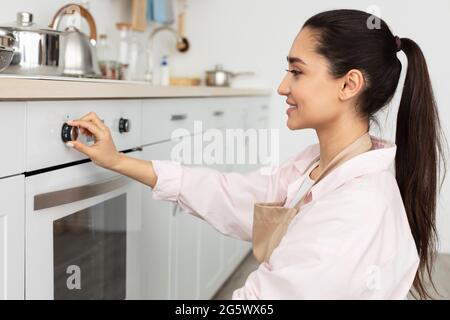 Smiling woman using stove cooking food in kitchen Stock Photo