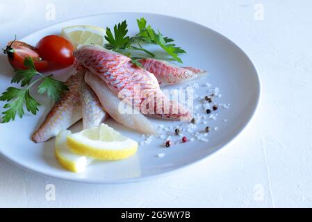 Fresh gurnard fillet with lemon on white plate. Stock Photo