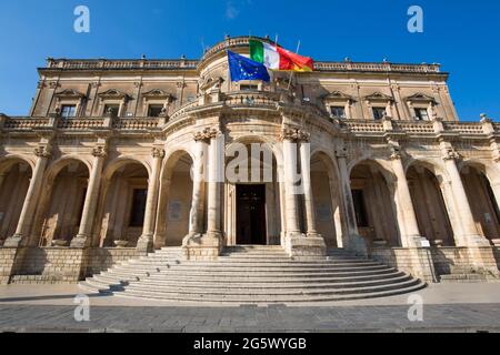 Noto, Syracuse, Sicily, Italy. Low angle view across Corso Vittorio Emanuele to the colonnaded façade of the Palazzo Ducezio, now the Town Hall. Stock Photo