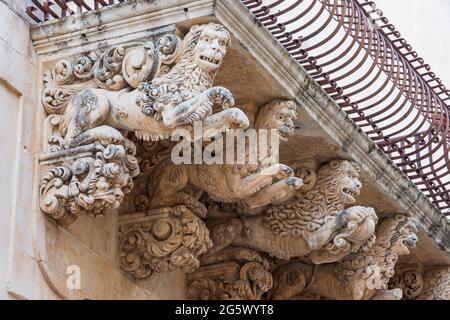 Noto, Syracuse, Sicily, Italy. Finely carved stone figures supporting ornamental balcony on the baroque façade of the Palazzo Nicolaci di Villadorata. Stock Photo