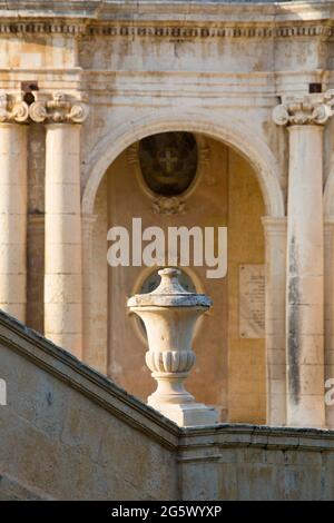 Noto, Syracuse, Sicily, Italy. Sunlit ornamental urn on steps of the Cathedral of San Nicolò, the Palazzo Ducezio, now the Town Hall, in background. Stock Photo