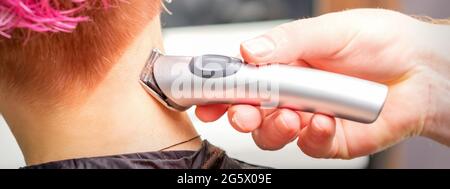 Back view of hairdresser's hand shaving nape and neck with electric trimmer  of a young caucasian woman with short pink hair in a beauty salon Stock  Photo - Alamy