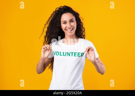 Woman showing volunteer text on her uniform t-shirt, studio shot Stock Photo