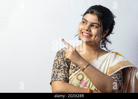 Isolated on white background an Indian woman in saree with smiling face looking sideways and pointing to empty space for advertising Stock Photo
