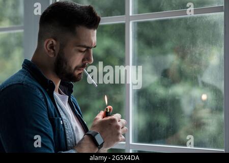 Urban lifestyle, emotional portrait of young handsome man sad and depressed, smoking Stock Photo