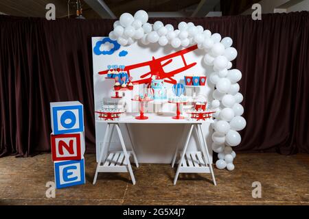 Candy bar on boy's birthday party with a lot of different candies, popcorn, beverages and big cake. Decorated in blue,red and white colors, balloons o Stock Photo
