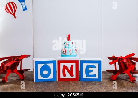Photo zone on boy's first birthday party with airplanes and big cake. Decorated in blue,red and white colors, balloons or aviation theme, indoor Stock Photo