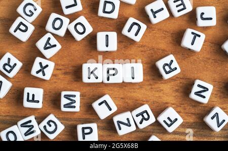 Small white and black bead cubes on wooden board, letters in middle spell KPI - Key Performance Indicators concept Stock Photo