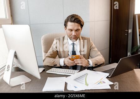 Handsome pensive caucasian businessman hold mobile phone distracted from work conference online, self-employed man solve business issues, have a break Stock Photo