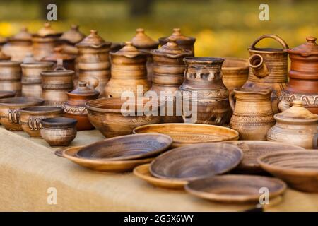 A lot of pottery - pots, jars, bowls, plates with ornaments are standing on the stall. Handmade dishes made of clay Stock Photo