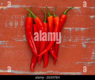 Plan view of red chilli peppers on a brown and blue wooden background. Stock Photo