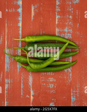 Plan view of green chilli peppers on a brown and blue  wooden background. Stock Photo